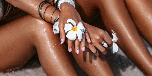 Frauenbeine mit weißer Blume am Strand